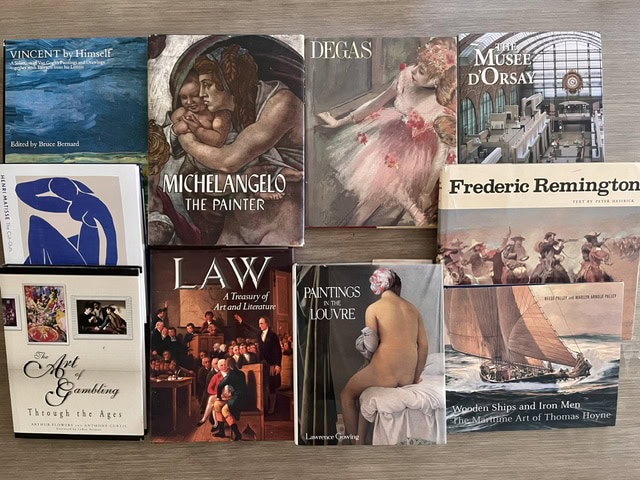 The Friends' book auction table. Book titles: Vincent by Himself, Michelangelo the Painter, Degas, The Musee D'Orsay, Henri Matisse: The Cut-Outs, The Art of Gambling Through the Ages, Law: A Treasury of Art and Literature, Paintings in the Louvre, and Wooden Ships and Iron Men: The Maritime Art of Thomas Hoyne.
