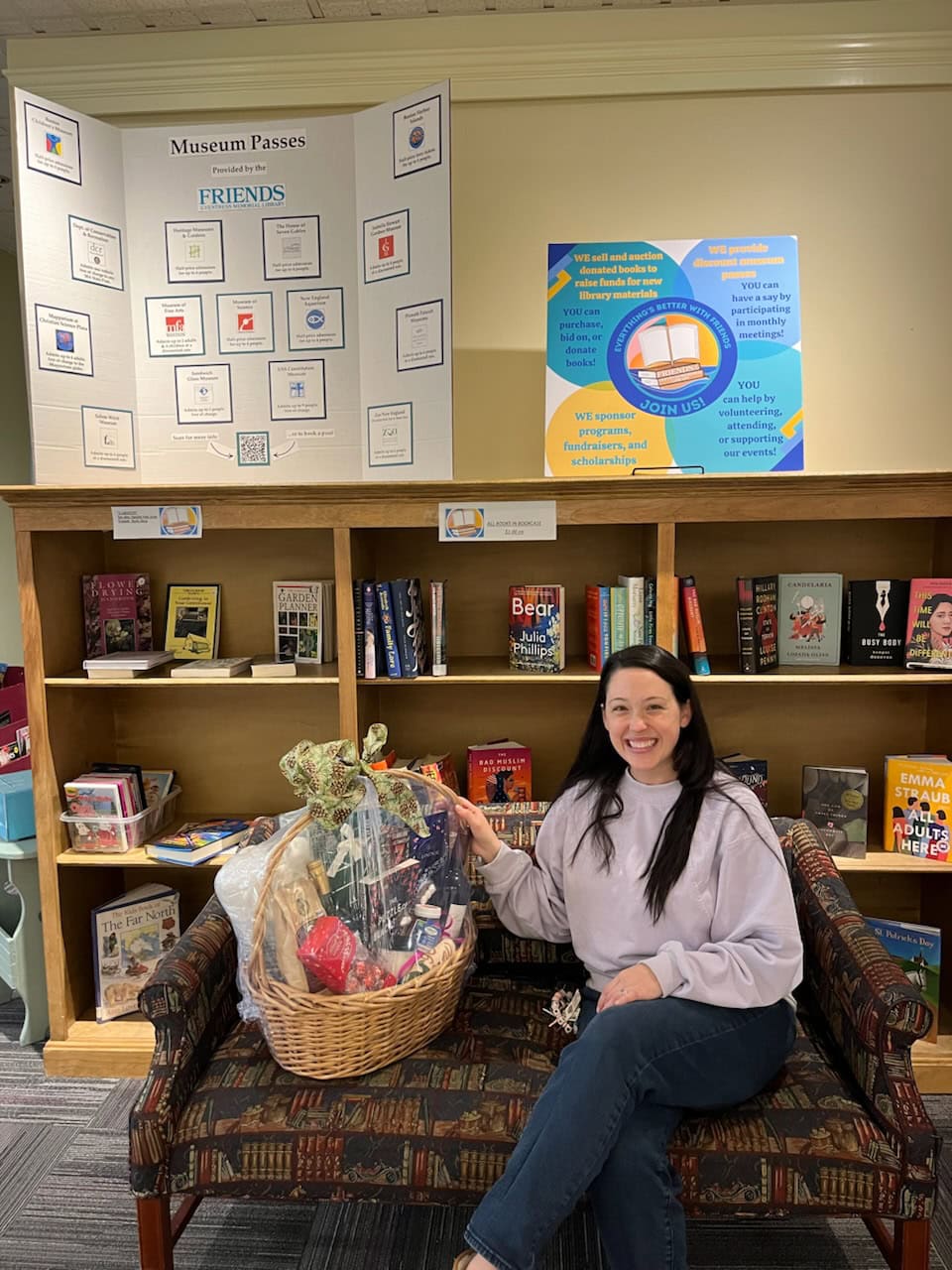 A woman poses with a raffle basket she has won in the Friends' book sale area.